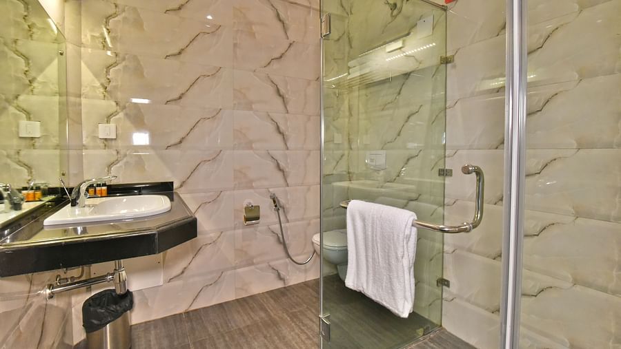 A shower cubicle with a wash basin beside it at DLS Hillcrest Resort, Shimla.